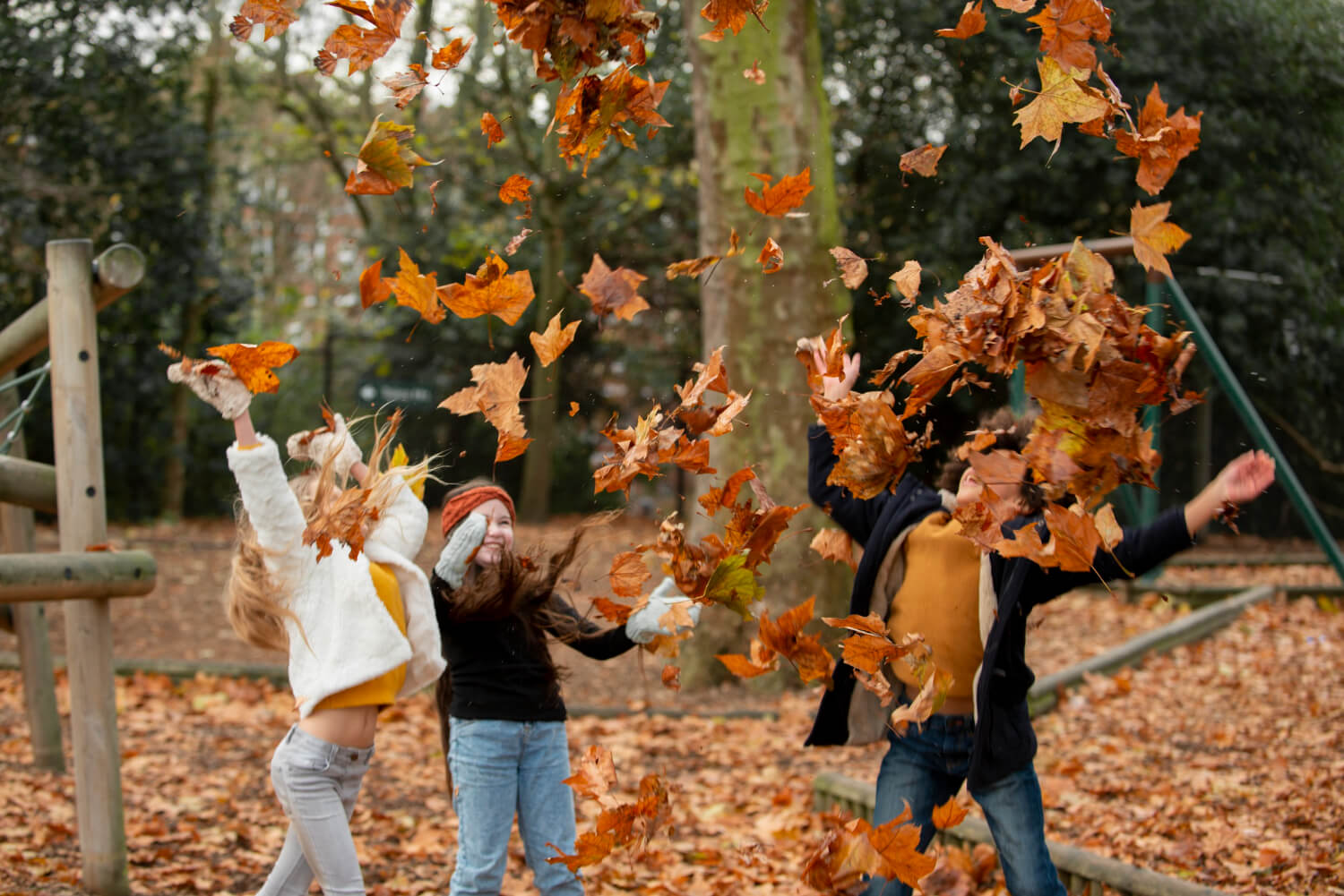 Kids playing with fallen autumn leaves